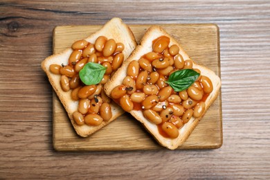 Toasts with delicious canned beans on wooden table, top view