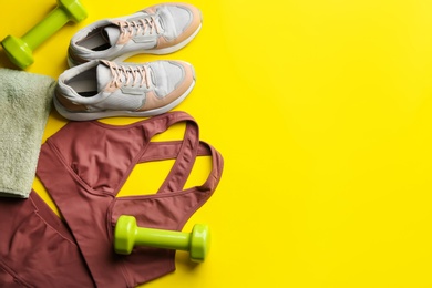 Flat lay composition with sportswear and equipment on yellow background, space for text. Gym workout