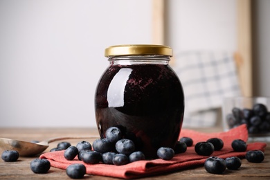 Jar of blueberry jam and fresh berries on wooden table