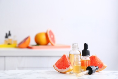 Bottles of essential oil and grapefruit slices on table. Space for text