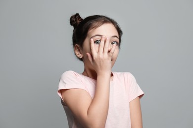 Little girl feeling fear on grey background