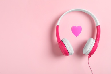 Modern headphones and heart on pink background, flat lay with space for text. Listening love music songs