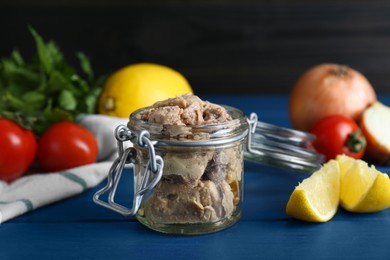 Photo of Glass jar of tasty cod liver and different products on blue wooden table