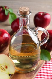 Jug of tasty juice and fresh ripe red apples on wooden table, closeup