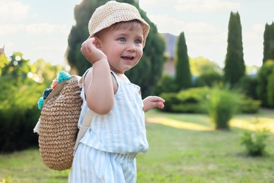 Cute little girl in stylish clothes with knitted backpack outdoors on sunny day. Space for text