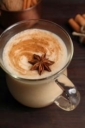 Photo of Delicious eggnog with spices on wooden table, above view