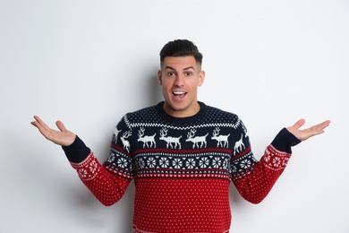 Surprised man in Christmas sweater on white background