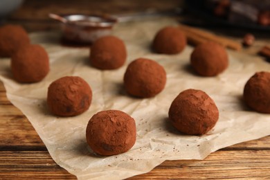 Delicious chocolate truffles powdered with cocoa on wooden table, closeup