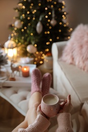 Woman holding cup of cocoa at home, closeup. Christmas mood