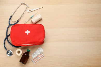 First aid kit on light wooden table, flat lay. Space for text
