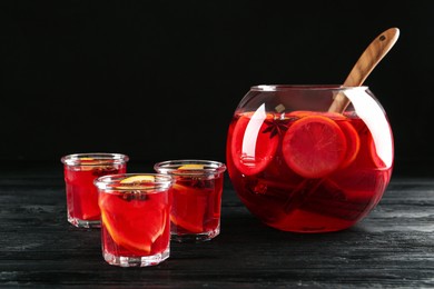 Bowl and glasses of delicious aromatic punch drink on black wooden table