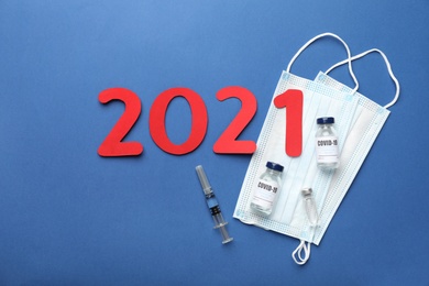 Flat lay composition with coronavirus vaccine and number 2021 on blue background