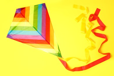 Bright rainbow kite on yellow background, top view