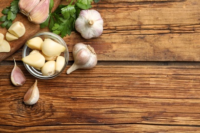 Flat lay composition with fresh garlic bulbs and cloves on wooden table, space for text. Organic product