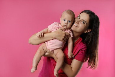 Beautiful mother with her cute baby on pink background