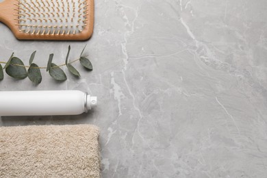 Dry shampoo spray, hairbrush, towel and eucalyptus on light marble grey table, flat lay. Space for text