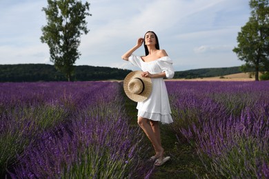 Beautiful young woman walking in lavender field