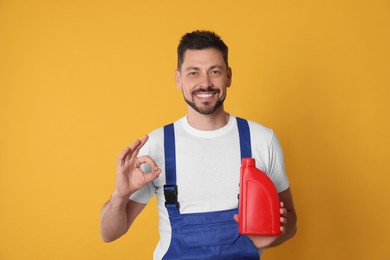 Man holding red container of motor oil and showing OK gesture on orange background