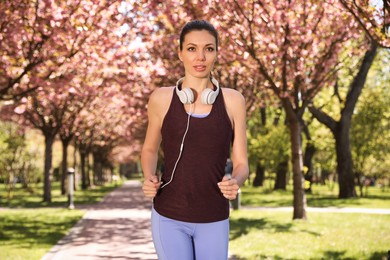 Woman with headphones on morning run in park. Fitness lifestyle