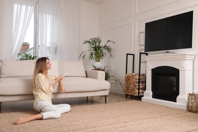 Young woman watching television at home. Living room interior with TV on fireplace