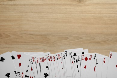 Photo of Deck of playing cards on wooden table, flat lay. Space for text
