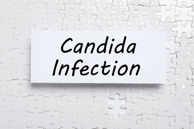 Card with phrase Candida Infection on white puzzle pieces, top view