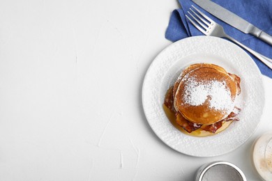 Delicious pancakes with maple syrup, sugar powder and fried bacon on white table, flat lay. Space for text