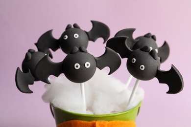 Delicious bat shaped cake pops on pink background, closeup. Halloween treat