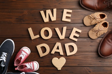 Flat lay composition with shoes and words WE LOVE DAD on wooden background. Father's day celebration