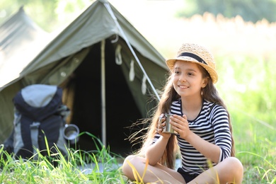 Little girl with mug near tent outdoors. Summer camp