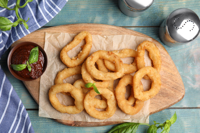 Fried onion rings served on blue wooden table, flat lay