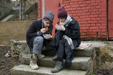 Poor young couple with bread on dirty street