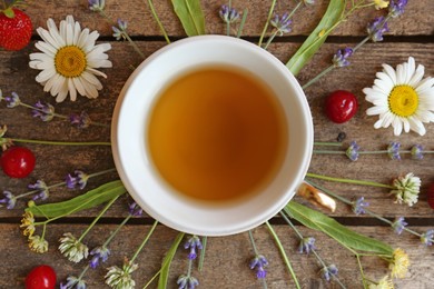 Tasty herbal tea, flowers and fruits on wooden table, flat lay