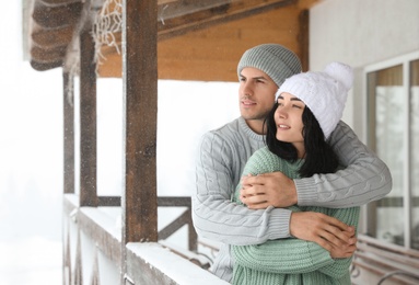 Lovely couple wearing warm sweaters and hats outdoors on snowy day. Winter season