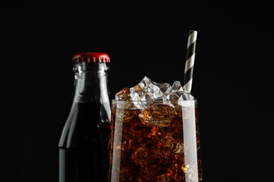 Photo of Bottle and glass of refreshing soda water on black background, closeup