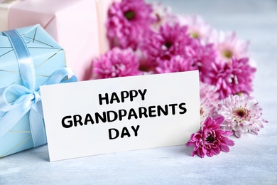 Beautiful flowers, gift boxes and card with phrase Happy Grandparents Day on grey table
