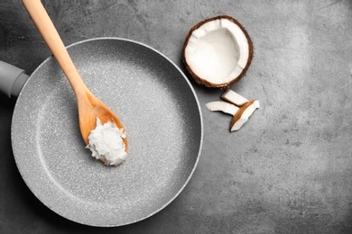 Frying pan with coconut oil and nut pieces on grey background