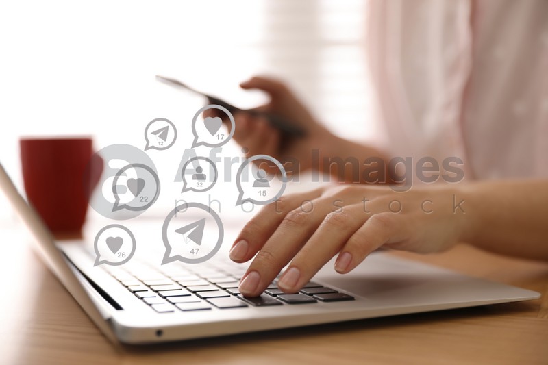 Different virtual icons and young woman using laptop and smartphone at table indoors, closeup. SMM (Social media marketing) concept