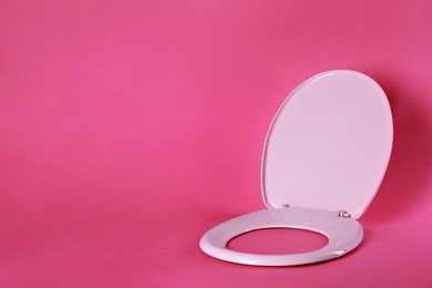 New plastic toilet seat on pink background, space for text