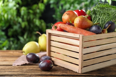 Crate full of different vegetables and fruits on wooden table outdoors, closeup. Harvesting time