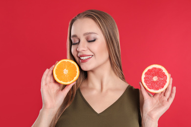 Photo of Young woman with cut orange and grapefruit on red background. Vitamin rich food
