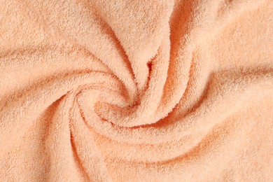Soft crumpled pale orange towel as background, top view