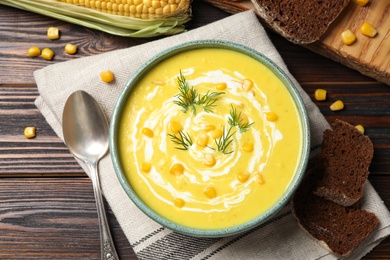 Delicious creamy corn soup served on wooden table, flat lay