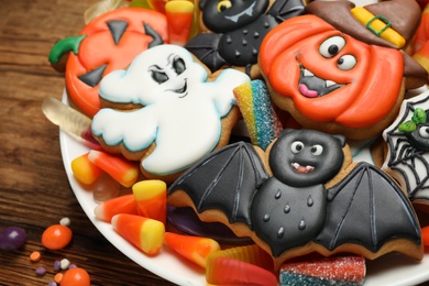 Tasty cookies and sweets for Halloween party on wooden table, closeup