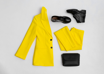 Stylish ankle boots, handbag and yellow office suit on white background, top view