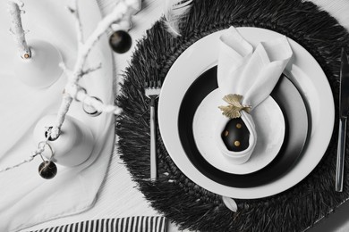 Photo of Festive table setting with bunny ears made of black egg and napkin, above view. Easter celebration