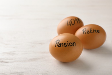 Eggs with words PENSION, RETIRE and 401k on wooden background. Space for text