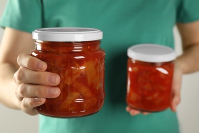 Woman holding jars of canned lecho, closeup