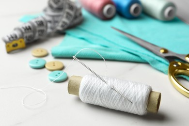 Photo of Threads and other sewing supplies on white marble table, closeup