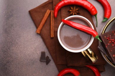 Photo of Cup of hot chocolate with chili pepper on grey table, flat lay. Space for text